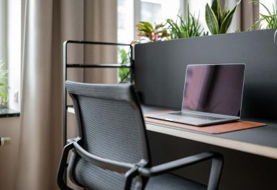 Focused workstation area with a laptop on a black desk and integrated planters.