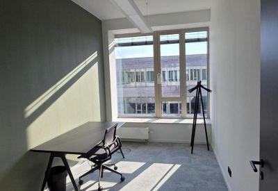 Bright private office featuring a dark wood desk and a large window with city views.
