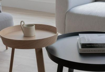 Modern lounge area featuring round wooden and black coffee tables and a plush grey sofa.