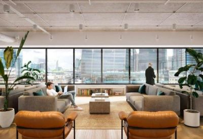 Spacious communal lounge with grey sofas, indoor plants, and large windows overlooking the city.