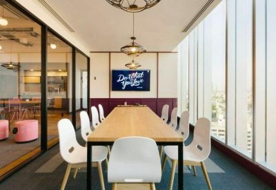 Bright boardroom featuring a long wooden table, white chairs, and floor-to-ceiling windows.