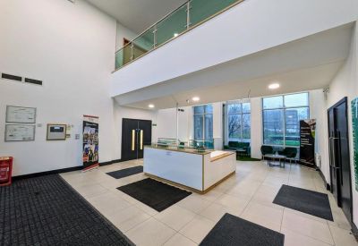 Spacious building lobby featuring a white reception desk and glass-paneled mezzanine level.