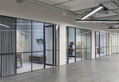 Spacious open-plan corridor with polished wood-style flooring and sleek glass office pods.