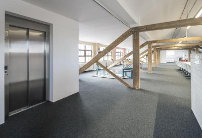 Modern elevator lobby area with rustic wooden structural beams and an open view into the office floor.