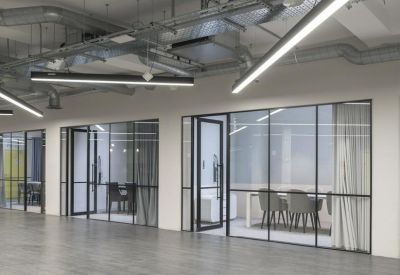 Modern hallway featuring glass-partitioned meeting rooms and industrial exposed ceiling ductwork.