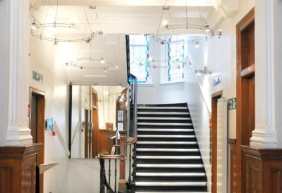 Grand lobby entrance featuring a checkered floor, classic staircase, and circular chandeliers.