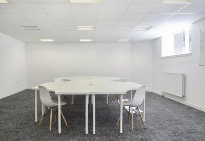 Bright white coworking space with modular desks and grey carpeting.