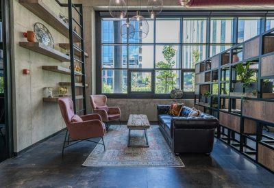 Relaxed lounge area with velvet armchairs, a leather sofa, and large windows.
