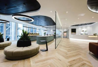 Spacious reception lounge with curved seating and herringbone wood flooring.