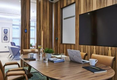 Boutique meeting room with wood-paneled walls, an oval table, and stylish tan leather chairs.