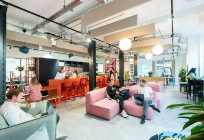 Spacious communal lounge area with pink modular sofas and a bright orange breakfast bar.