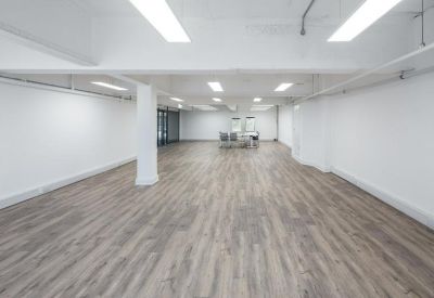 Spacious, empty workspace featuring white walls, pillars, and a light wood-toned floor.