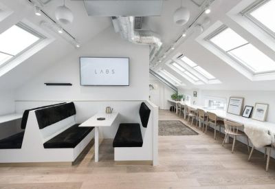 Bright attic workspace with a communal dining booth and long desk under skylights.