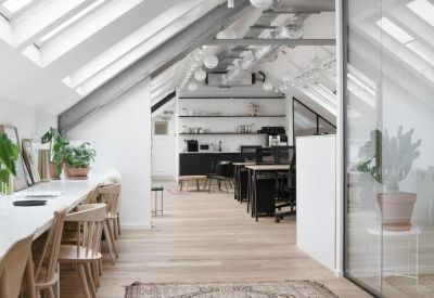 Open-plan office with timber flooring and workstations situated under a pitched roof.