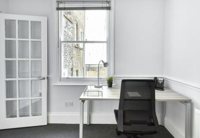 Individual workstation in a private office featuring a white desk and large sash window.