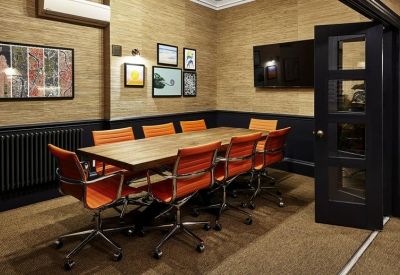 Professional meeting room with a large wooden table, orange leather chairs, and wall-mounted TV.