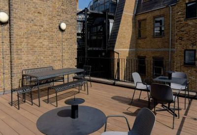 Outdoor rooftop terrace with wooden decking and black metal seating areas.