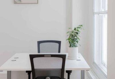 Modern workstation with white desk, ergonomic black chairs, and a potted plant.