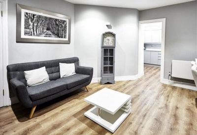 Modern lounge area with a grey sofa, white coffee table, and wood flooring.