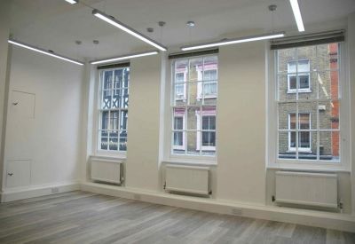 Bright open-plan office space with wood-style flooring and large sash windows.