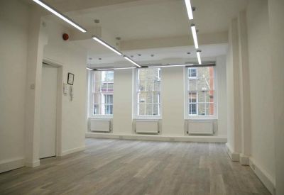 Spacious empty workspace featuring overhead strip lighting and neutral white walls.