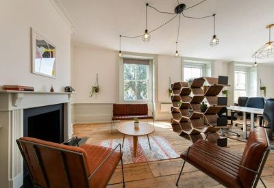 Bright communal lounge featuring tan leather chairs, a fireplace, and a unique honeycomb bookshelf.
