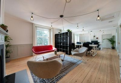 Spacious open-plan office with high ceilings, spider-style lighting, and various seating areas.