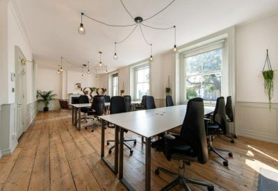 Meeting area with long white tables, professional seating, and warm wood flooring.