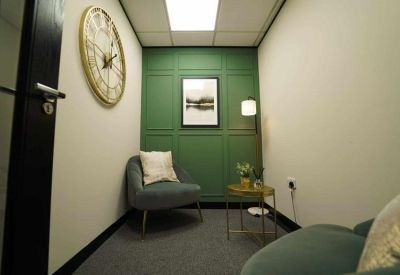 Small private meeting pod with a green panelled wall and comfortable armchair.