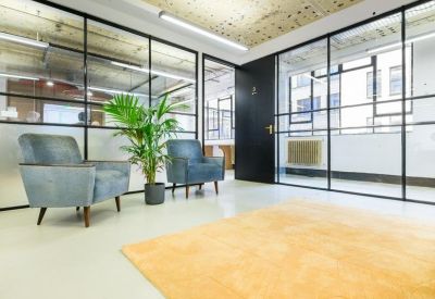 Modern waiting area featuring blue velvet armchairs and a glass partition wall.