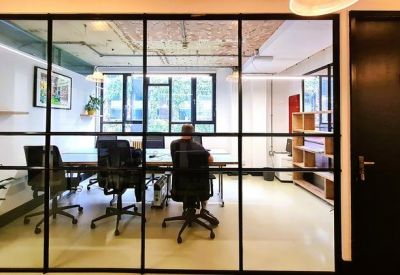 View into a glass-partitioned office with desks and black mesh chairs.