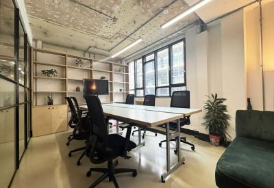 Bright boardroom with a white table, black ergonomic chairs, and large windows.