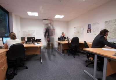 Shared office space with several workstations and wall-mounted maps.