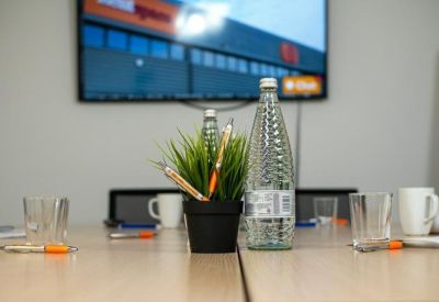 Conference table setup for a meeting with water bottles, glasses, and pens.