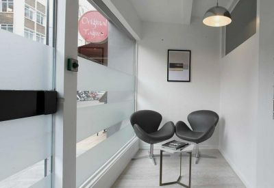 Small reception area featuring two black designer chairs and frosted glass windows.