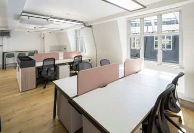 Open-plan office with white desks, ergonomic chairs, and pink privacy screens.