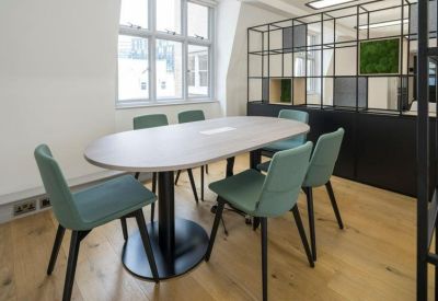 Contemporary meeting space with a light wood oval table and teal chairs.