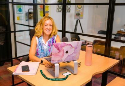 Bright workspace with a laptop on a stand and glass partitioned walls.