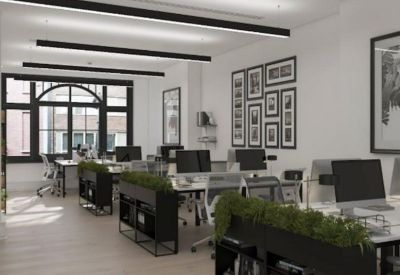 Open-plan office space with black desks, greenery planters, and large windows.