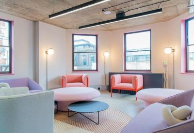 Vibrant breakout lounge featuring pink and purple circular sofas and armchairs by large windows.