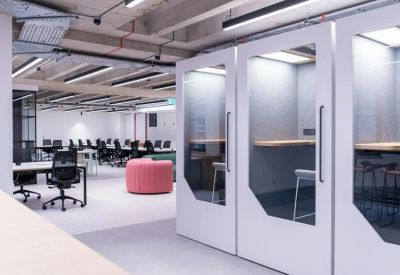 Contemporary coworking space featuring private white phone booths and open-plan desks in the background.