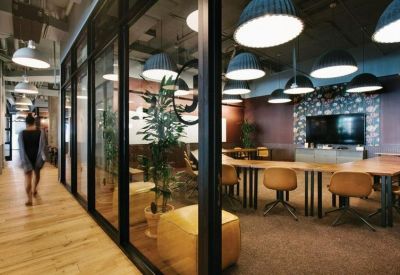 Sleek glass-walled meeting room with long wooden tables and blue pendant lighting.
