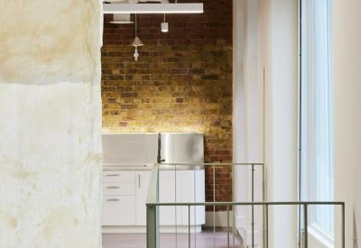 Detail view of an upper level mezzanine with white railings and a kitchen area in the background.