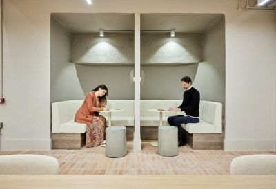 Semi-private meeting booths with white upholstered seating and integrated lighting.