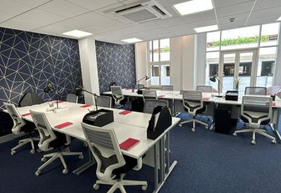 Shared office space with multiple desks and chairs.