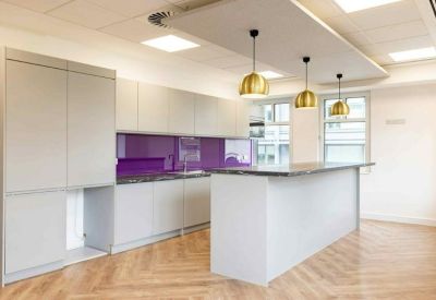 Modern kitchen and break area with a purple backsplash and gold pendant lights.