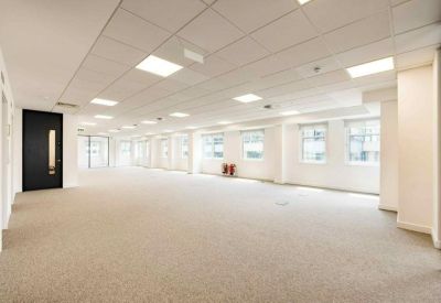 Spacious open-plan office with white walls and grey carpet.