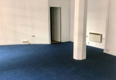 Spacious open-plan office with blue carpet and a central white structural column.
