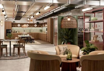 Breakout lounge with comfortable armchairs, a kitchen island, and industrial ceiling details.