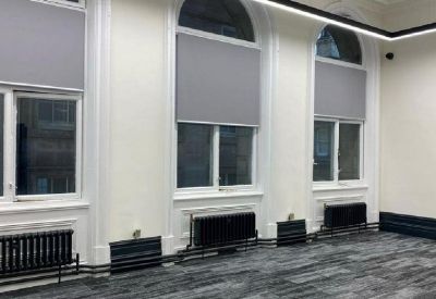 Renovated open office area featuring large arched windows and grey carpet.